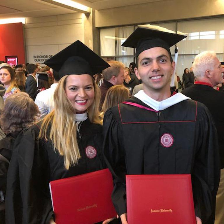 Two students smiling with graduation gowns