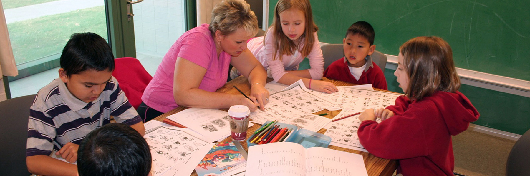 Teacher showing children coloring handouts in a classroom